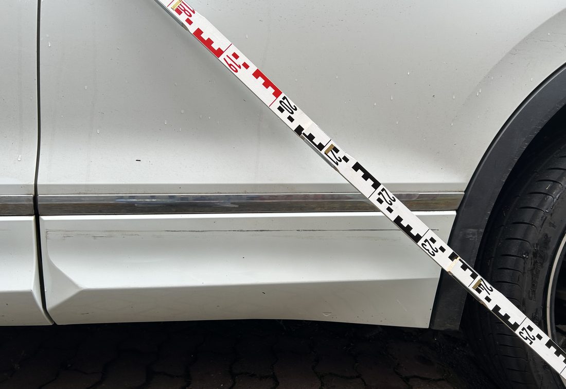 Streifschaden an Tür und Schweller eines weißen VW Tiguan, mit Messlatte dokumentiert, Schadengutachten über 2.585,91 €