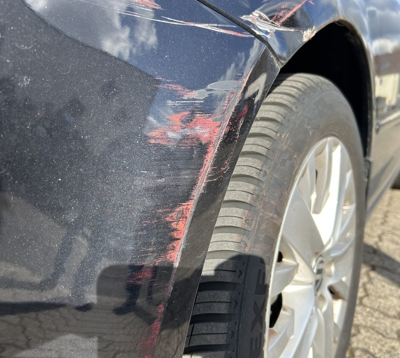 Kfz-Sachverständiger dokumentiert einen Kotflügelschaden mit Messlatte bei der Schadenaufnahme